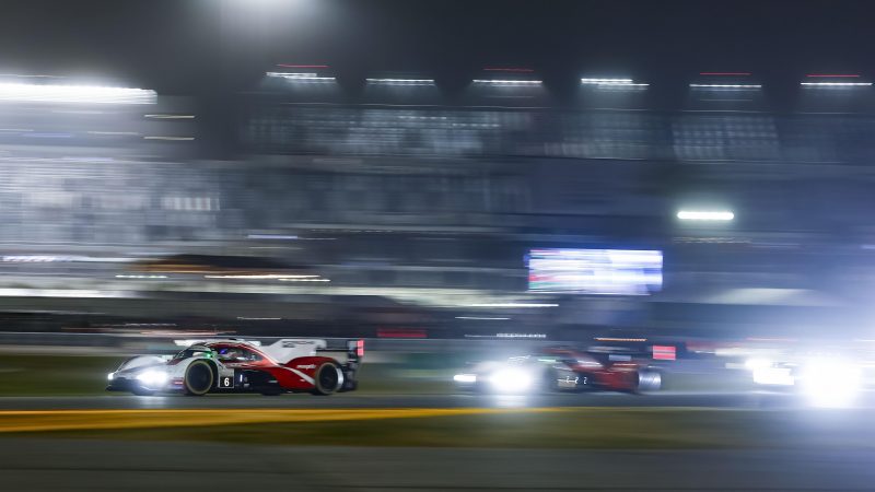 Two Porsche Penske Motorsport cars battle in the night at the Rolex 24 at Daytona 2026